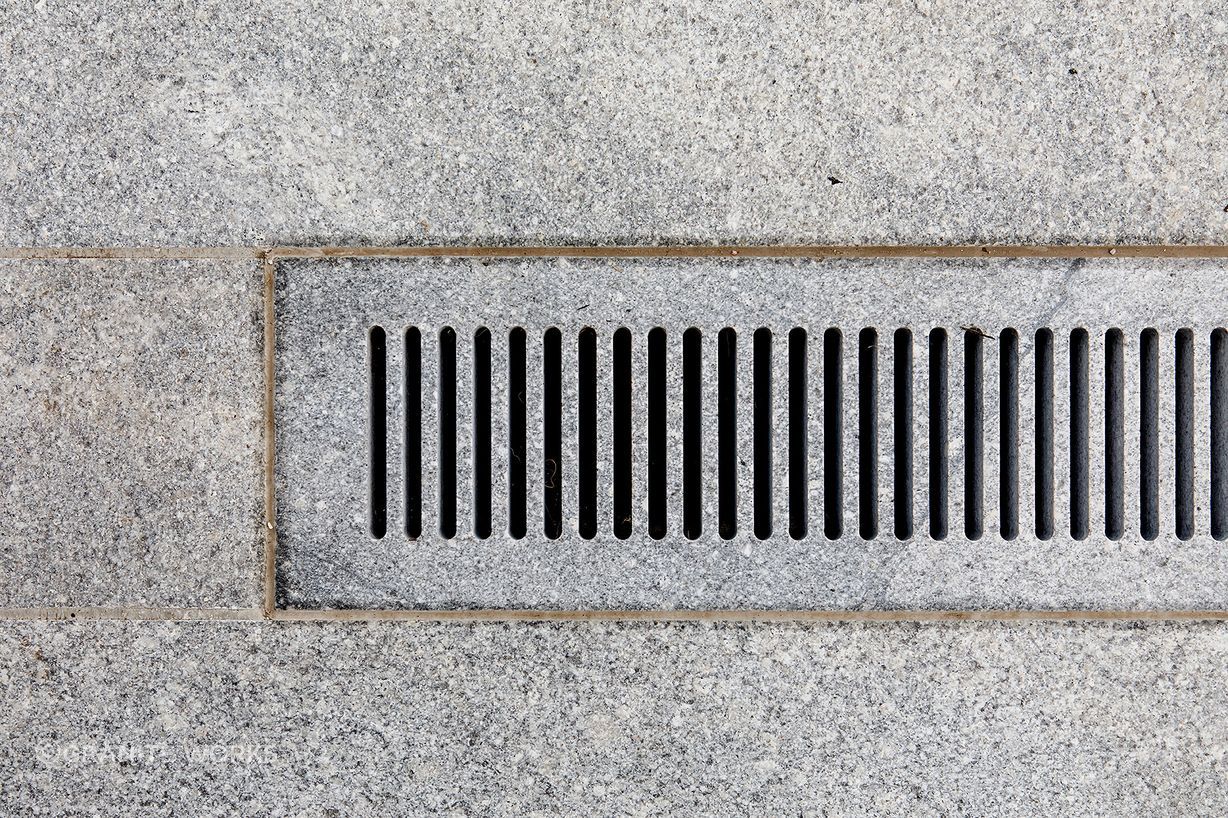 A stone grate runs along the pool's length as the primary drainage point.