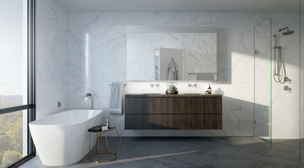 A bright, contemporary bathroom featuring a freestanding white bathtub beside full-height glazing, a wall-mounted dark wood vanity with double basins, large white marble-look wall panels, a frameless glass shower enclosure, and dark herringbone-pattern flooring. Natural light creates a calm, refined atmosphere.