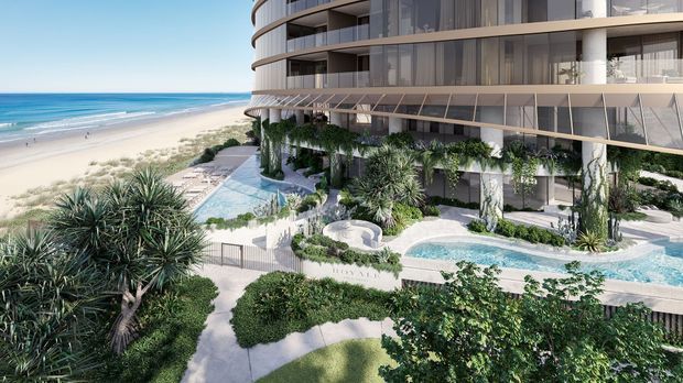 A photorealistic architectural rendering of a contemporary multi-storey beachfront apartment or hotel building with sweeping curved balconies and extensive glass glazing. The landscaped resort-style grounds include a swimming pool, pale paved terraces, sculptural seating, dense subtropical planting, and pedestrian paths, with a sandy beach and ocean directly beyond.