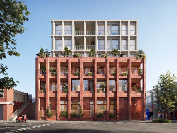 Architectural rendering of a contemporary multi-storey apartment building in an urban streetscape. The lower levels feature a strong red brick facade with repetitive vertical bays, recessed balconies, planting, and dark-framed glazing, while the upper levels transition to a light rendered or concrete facade with projecting frames and open balconies. Street trees and neighbouring buildings frame the composition.