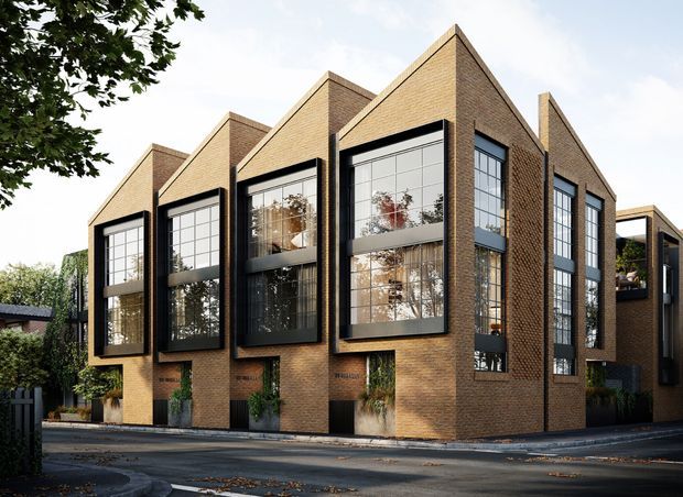 Contemporary multi-storey brick residential building with a rhythmic series of steeply pitched gabled bays and large black-framed industrial-style windows. The facade combines warm brown brickwork, dark metal window surrounds, recessed entries, planting, and projecting upper-level balconies, presenting a refined urban streetscape.
