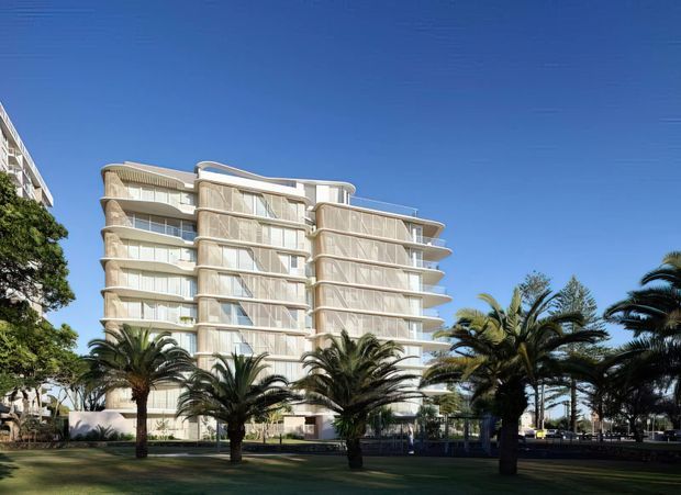 Exterior architectural view of a contemporary multi-storey apartment building with rounded corners, extensive curved balconies, pale cream facade panels, and large glazed openings. Palm trees and landscaped grounds occupy the foreground under a clear blue sky.
