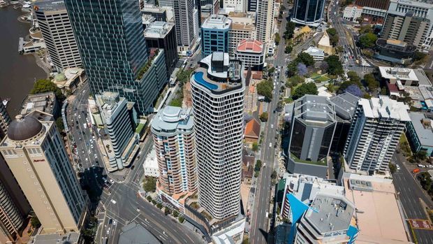 Aerial view of a dense urban commercial and high-rise district, showing multiple modern towers, apartment buildings, streets, and a waterfront edge. The image is dominated by the exterior cityscape and building forms.