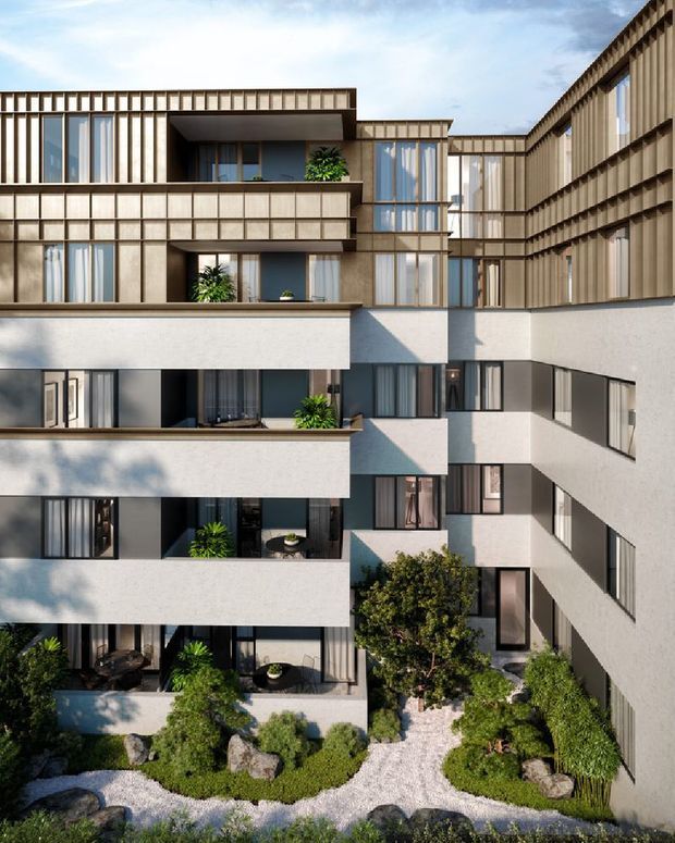 Architectural rendering of a multi-storey contemporary apartment development arranged around a landscaped internal courtyard. The building features stepped balconies, recessed terraces, extensive glazing, pale rendered walls, and warm vertical timber-look facade screening. A Japanese-inspired garden with gravel, rocks, shrubs, and small trees occupies the foreground.