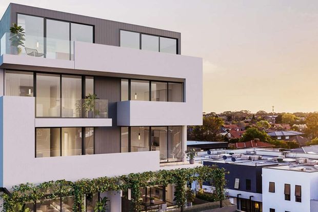 Contemporary multi-storey residential building with a white rendered facade, dark vertical cladding, extensive black-framed glazing, projecting balconies, rooftop terraces and planted trellis elements. The image is an exterior architectural view overlooking a suburban neighbourhood in warm evening light.