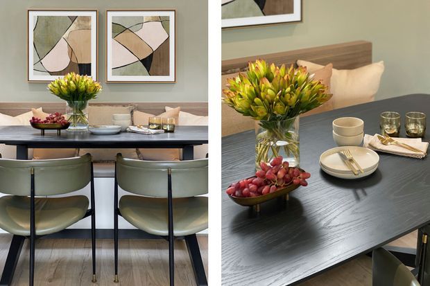 A styled dining area with a dark rectangular dining table, upholstered dining chairs, a wood-panelled banquette, and layered table settings. Abstract framed artwork hangs on a muted green wall, while a vase of flowers and a bowl of fruit provide centrepieces. The room has a refined, contemporary look with warm timber flooring and soft neutral upholstery.