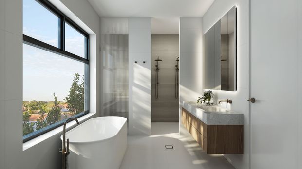 Bright contemporary bathroom with a freestanding white bathtub beside large black-framed windows, a walk-in dual shower zone with textured wall tiles, and a floating timber vanity with a pale stone benchtop and large illuminated mirror. The space has clean white surfaces and abundant natural light, with a leafy suburban outlook visible through the glazing.