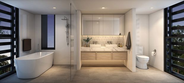Contemporary open-plan bathroom with a freestanding white bathtub, frameless glass shower enclosure, wall-mounted double vanity with light timber drawer fronts, mirrored upper cabinetry, and a separate toilet. Dark-framed louvred glazing on both sides brings in greenery and natural light. The palette is warm neutral with pale walls, beige stone-look flooring, and black accents.