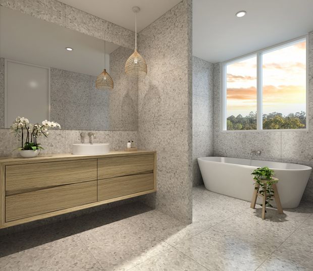 A refined contemporary bathroom featuring a floating timber vanity with a white vessel basin, large wall-to-wall mirror, freestanding white bathtub, and textured light stone-look wall and floor finishes. Woven pendant lights add warmth, while a large window provides natural light and views of trees and sky.