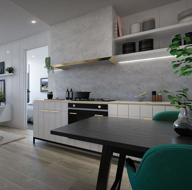 A contemporary kitchen with a long wall of pale built-in cabinetry, a dark benchtop and matching dining table, black appliances, open shelving, and a large textured grey splashback or feature wall. Green upholstered dining chairs, potted plants, and dark decorative accessories add contrast. Timber-look flooring and a partially visible adjoining bedroom or hallway appear at the left.