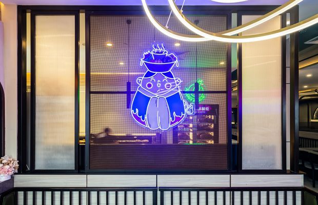 A dark, contemporary commercial interior frontage featuring black-framed fluted translucent glass panels, a central illuminated neon cartoon graphic, linear built-in cabinetry or ledge below, and a curved illuminated ceiling feature. The space has a dramatic purple-blue ambient glow and appears to be a restaurant, bar, or entertainment venue.