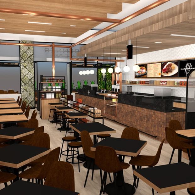 A contemporary commercial café or fast-casual restaurant interior with extensive dining seating, a service counter, menu boards, display shelving, and decorative lighting. The space combines black tabletops, dark timber seating, a brick-faced counter, timber ceiling and wall cladding, copper-toned exposed services, and bright pendant lights.