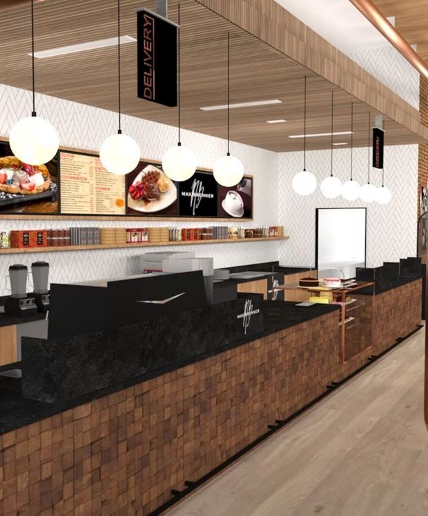 Interior view of a contemporary commercial café or takeaway venue, with long black stone service counters clad in small brown brick tiles, menu and display boards, pendant globe lighting, timber slatted ceiling, patterned white wall finish, shelving, and food-preparation equipment.