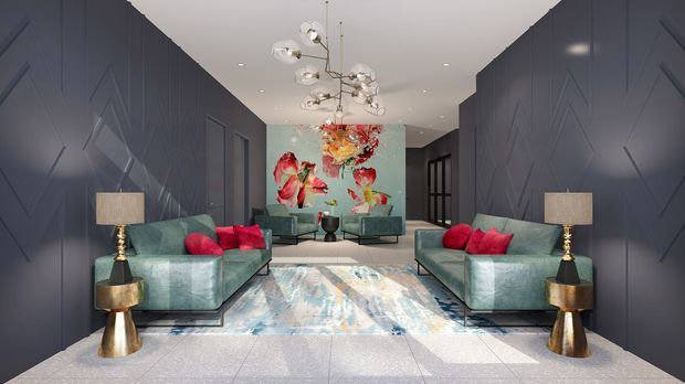 A dramatic, symmetrical contemporary living room or lounge with deep blue-grey geometric wall panelling, pale polished flooring, two large blue-grey sofas with vivid red cushions, metallic side tables and lamps, a sculptural branching pendant light, and a colourful floral feature artwork at the far end. The space has a refined, high-contrast and luxurious feel.