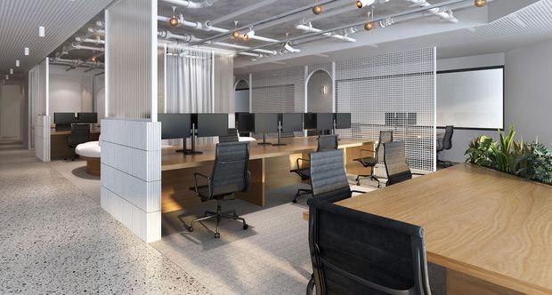 Contemporary open-plan commercial office with shared timber workstations, black office chairs, exposed ceiling services, terrazzo-style flooring, perforated metal screening, and indoor planting. A meeting or presentation area with a projection screen is visible at the rear.