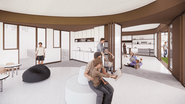 A bright, spacious contemporary communal interior with a curved ceiling and open-plan layout. Large glazed windows and doors, white built-in cabinetry and shelving, warm brown timber-toned framing, and a pale speckled floor surround informal seating and several people engaged in social or recreational activities. The space appears multi-purpose, with a central curved white seating element, beanbag, tables, and open circulation areas.