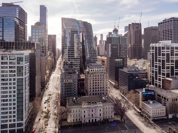 Aerial urban view of a dense downtown district, showing numerous high-rise office and residential buildings, broad city streets, construction cranes, and a prominent historic neoclassical building in the foreground. The scene has a contemporary metropolitan character with mixed modern and heritage architecture.