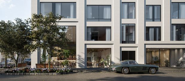Street-level architectural rendering of a contemporary multi-storey mixed-use or residential building with a pale rendered masonry facade, strong vertical window bays, large ground-floor glazed spaces, and upper-level apartments or offices. Mature street trees, planted beds, bicycles, outdoor seating, and a parked vintage car animate the frontage.