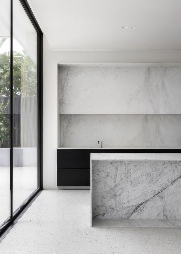 A minimalist contemporary kitchen with a black-framed floor-to-ceiling glazed wall, matte black lower cabinetry, a pale veined stone island, and a matching pale stone backsplash and open shelving surround. The space is bright and monochromatic, with greenery visible beyond the glazing.