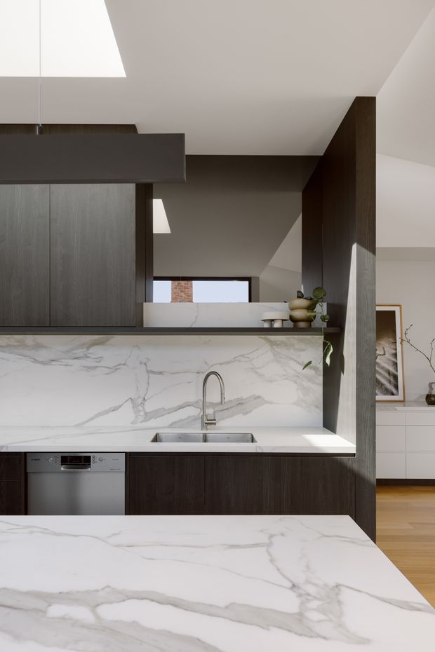 Contemporary kitchen with dark timber cabinetry, a large white marble-look island and matching splashback, stainless-steel sink and integrated dishwasher. A skylight and angled ceiling bring natural light into the space, with a glimpse of an adjacent living area beyond.