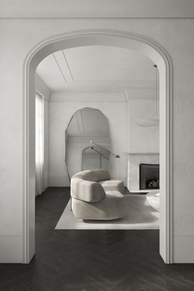A monochromatic, softly lit living room viewed through a large arched doorway. The room features dark herringbone timber flooring, white textured walls and ornate arched trim, a pale sculptural lounge chair on a light rug, a curved floor lamp, a large organic-shaped wall mirror, sheer curtains, and a white tiled or stone fireplace with a dark firebox. The overall composition is refined and minimalist with strong curved architectural details.