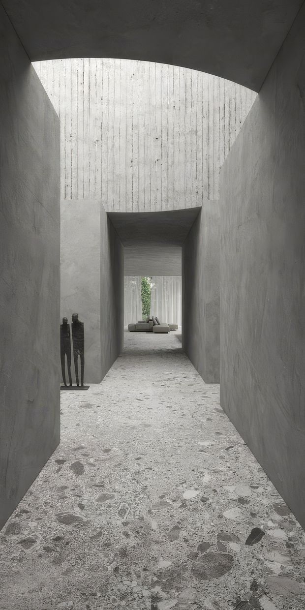 A dramatic minimalist interior passage with tall curved and angular concrete walls, a textured concrete ceiling, and a terrazzo-like aggregate floor. The corridor leads toward a softly furnished living area visible in the distance, with a narrow glimpse of greenery beyond. A dark sculptural object stands along the left wall. The composition emphasizes raw materiality, geometric openings, filtered daylight, and strong depth.