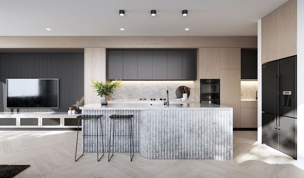 Contemporary open-plan kitchen with a large fluted island, integrated dark cabinetry, light timber-look wall cabinetry, pale timber flooring, and a black appliance bank. Two bar stools face the island, while a living area with a wall-mounted television is visible to the left. Recessed and under-cabinet lighting create a bright, refined interior.