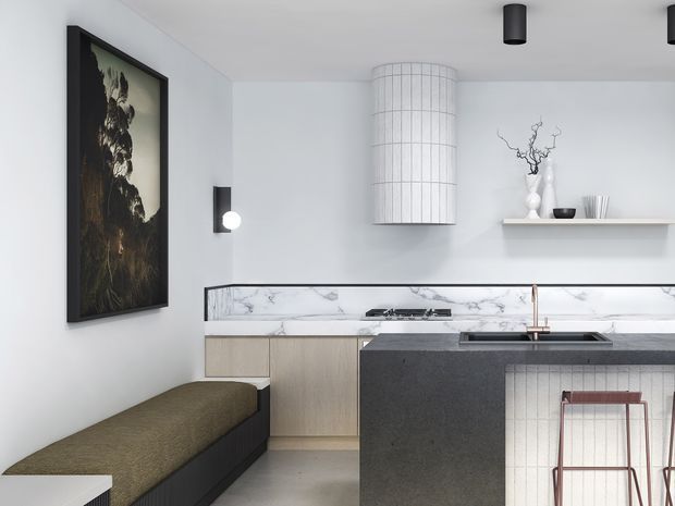 A refined contemporary kitchen with a dark stone island and integrated seating, pale timber cabinetry, a white marble-look splashback, and a curved cylindrical pendant light. A built-in upholstered bench sits beneath a large framed artwork, while open shelving displays decorative objects. The palette is restrained in white, grey, black, and muted olive tones.