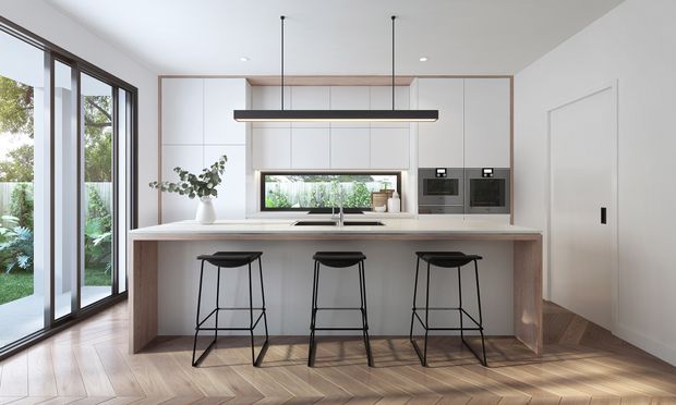 Bright contemporary kitchen with a large timber island and three black bar stools, white flat-panel cabinetry, integrated appliances, a slim linear pendant light, and a wide window above the sink. Full-height glazed doors open to a leafy garden, while warm timber flooring and subtle timber framing add warmth to the otherwise white interior.