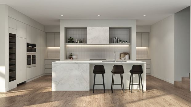 A refined contemporary kitchen with a large white marble island, integrated pale cabinetry, open display shelving, built-in appliances, a ribbed backsplash, and three dark bar stools. Warm timber flooring contrasts with the light neutral joinery, while recessed ceiling lights provide understated illumination. A partial stairway is visible at the right edge.