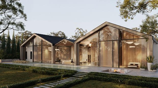 Contemporary single-storey residence with two connected steeply pitched gable volumes, extensive floor-to-ceiling glazing, dark metal roof elements, and warm timber interiors visible through the glass. The home is set within a manicured landscaped garden with clipped hedges, a paved path, and a narrow reflective pool or water feature along the facade. The exterior presentation is clean, refined, and warmly illuminated.