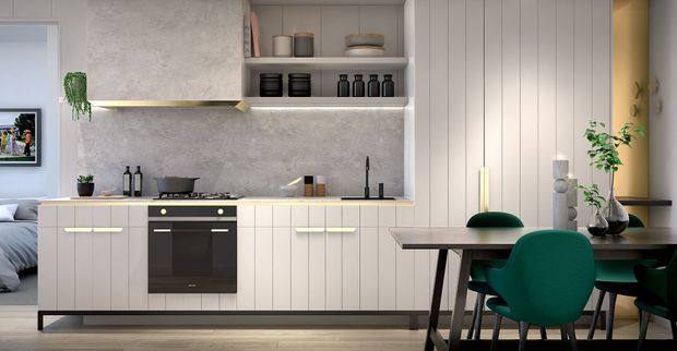A contemporary open-plan kitchen and dining area with pale vertical-panel cabinetry, a dark built-in oven, a light stone-textured backsplash and benchtop, open shelving, and integrated under-shelf lighting. A dining table with dark legs and deep green upholstered chairs occupies the foreground, while a bedroom is partially visible through the opening at left.