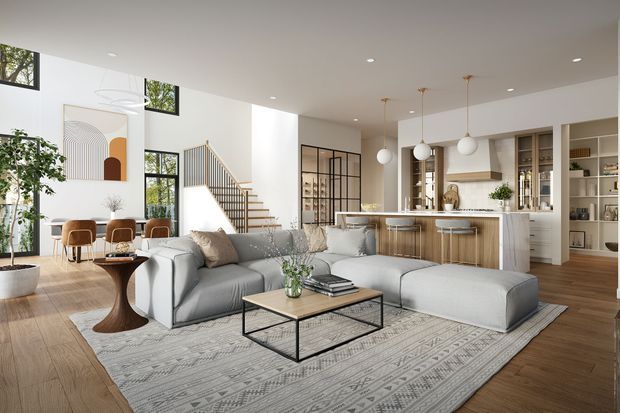A bright, open-plan contemporary home interior combining a living room, dining area, kitchen, and stairway. The room features large black-framed windows, light timber flooring, a pale grey sectional sofa, geometric area rug, slim black metal coffee table, white kitchen cabinetry, a timber island with bar seating, pendant globe lights, and a glazed black-framed partition near the stairs.