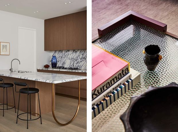 Split image showing a refined contemporary kitchen on the left, with a marble-look island benchtop, timber cabinetry, integrated sink and stools, and a close-up decorative vignette on a textured glass-topped table with books and a small vessel on the right.