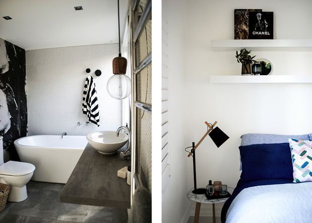 Split-view interior image showing a contemporary bathroom on the left and a bedroom on the right. The bathroom features a freestanding white bathtub, vessel basin on a dark timber vanity, patterned wall tiles, black-and-white artwork or wall treatment, and pendant lighting. The bedroom has white shiplap-style wall cladding, open white display shelves, a navy and white bed, patterned cushions, and a small bedside table with an angled floor lamp.
