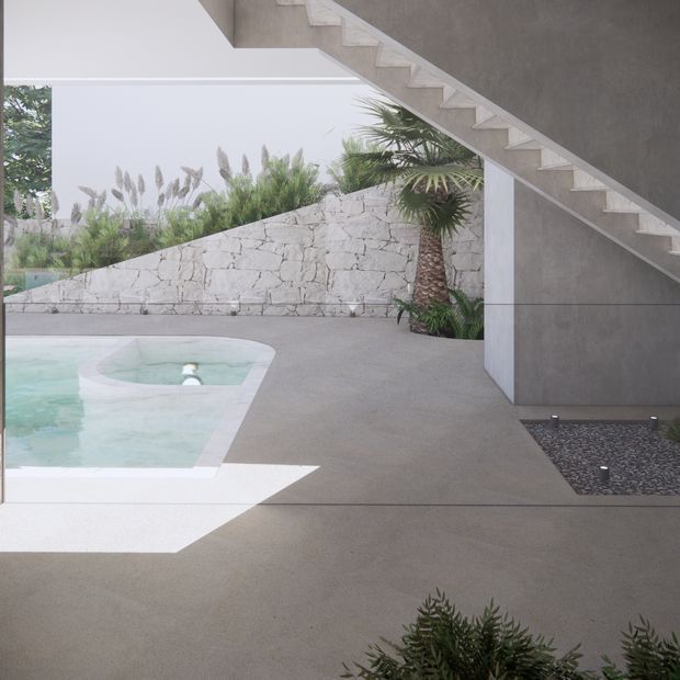 A minimalist modern outdoor pool courtyard beneath an exposed concrete staircase. The scene features a pale turquoise swimming pool with a rounded spa-like end, a broad smooth grey concrete terrace, a rough light stone retaining wall, tropical planting, and a dark pebble garden bed. Strong geometric lines and open glazing create a calm, contemporary architectural composition.