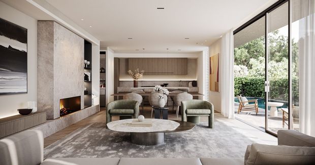 A refined contemporary open-plan living room with a built-in fireplace, sculptural stone feature wall, muted upholstered lounge chairs, a round coffee table, and a dining area with integrated timber cabinetry beyond. Full-height glazed sliding doors open to a leafy outdoor terrace, bringing in abundant natural light. The palette is warm and neutral, with pale stone, timber, taupe textiles, and soft grey furnishings.