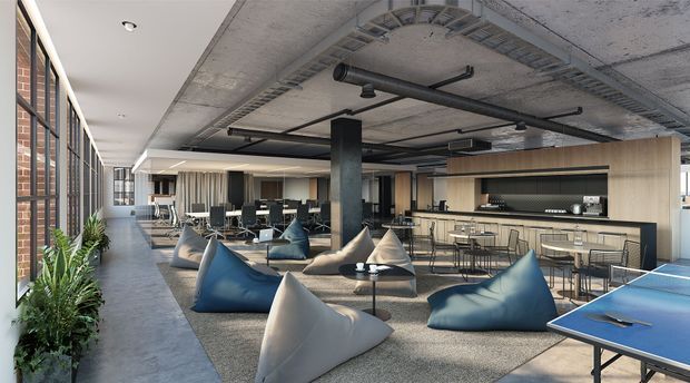 Open-plan industrial-style commercial interior combining a lounge, collaborative work area, and kitchenette/bar. The space features exposed concrete ceilings, black exposed services and ductwork, steel columns, expansive black-framed glazing, exposed brick, polished concrete flooring, timber-toned fixed cabinetry, and relaxed beanbag seating. A blue table-tennis table occupies the foreground, while desks and office chairs are arranged deeper in the space.