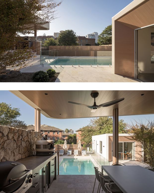 Two views of a contemporary residential outdoor entertaining area surrounding a rectangular swimming pool. The upper view looks across a paved pool terrace toward a glazed pool fence and a timber-clad pavilion, while the lower view shows a covered outdoor kitchen and dining area with a ceiling fan, built-in stainless-steel cabinetry and barbecue, natural stone retaining wall, and pool beyond. The setting is leafy and suburban, with warm timber soffits and pale paving.