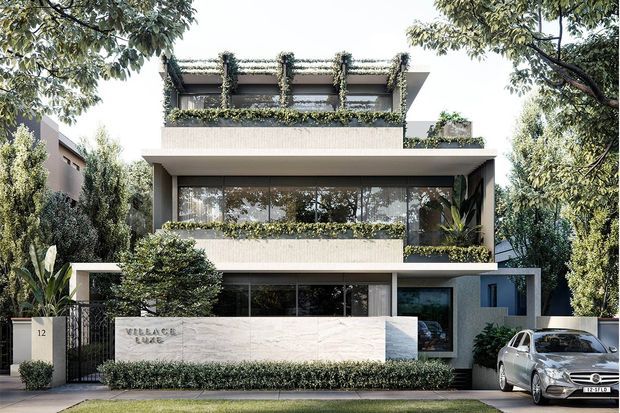 Front elevation of a refined multi-storey contemporary residence, featuring layered rectangular volumes, extensive dark-framed glazing, pale textured masonry or stone cladding, planted balcony edges, and a rooftop terrace with trailing greenery. A low entry wall and gated driveway define the landscaped frontage.