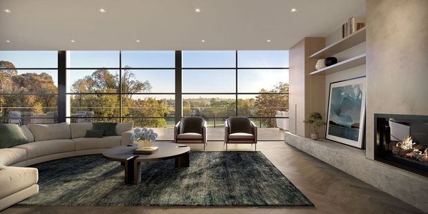 A spacious, refined contemporary living room with expansive floor-to-ceiling black-framed glazing overlooking a leafy landscape. The room features a large curved sectional sofa, sculptural coffee table, two lounge chairs, a dark textured area rug, warm timber-toned built-in shelving, an integrated fireplace, and a large framed artwork. Recessed ceiling lighting and neutral earthy finishes create a calm, luxurious atmosphere.