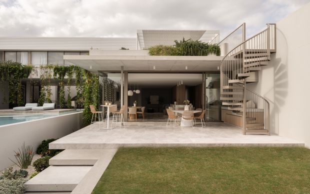 Contemporary multi-level residential courtyard viewed from the garden, featuring a broad covered outdoor entertaining terrace opening into a dark-toned living and dining area. A raised swimming pool sits to the left, with lush vertical planting and a sculptural external spiral staircase leading to an upper level. The architecture uses pale horizontal cladding, white rendered walls, concrete paving, extensive glazing, and clean rectilinear forms.