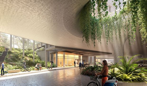 A high-end architectural rendering of a covered urban building entrance or lobby beneath a sweeping textured concrete canopy. The space features floor-to-ceiling glazing, warm timber-lined interior walls, paved flooring, lush built-in planting, hanging vines, pedestrians, bicycles, and a partially visible vehicle. The design creates a bright, biophilic, semi-outdoor arrival space with a large sculptural overhead form.