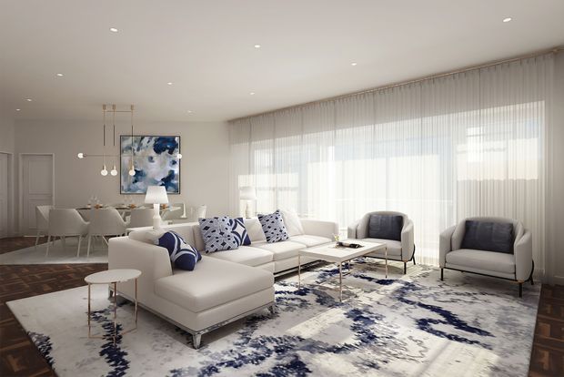 Bright, spacious contemporary living room with a large white sectional sofa, two sculptural armchairs, glass-topped coffee tables, and a blue-and-white patterned area rug. Full-height sheer curtains cover expansive glazing, while a dining area, pendant lights, recessed ceiling lights, and abstract artwork are visible in the background. The room has a refined, airy neutral palette with navy and blue accents.