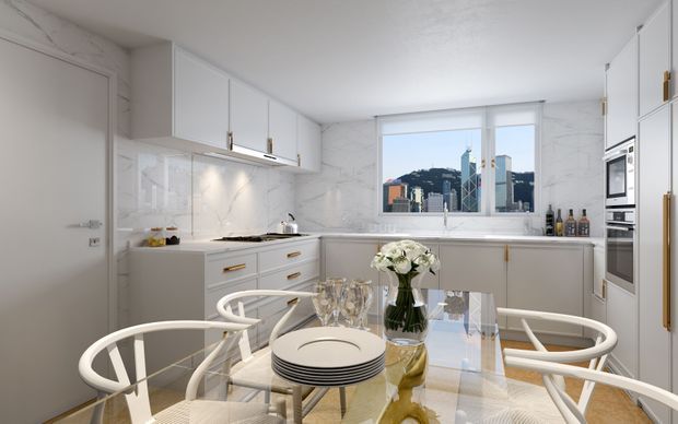 Bright white contemporary kitchen and dining area with extensive built-in cabinetry, marble-look wall surfaces, integrated appliances, a large window overlooking a dense urban skyline, and a glass dining table surrounded by white spindle-back chairs. Gold-toned hardware and a floral centrepiece add refined accents.