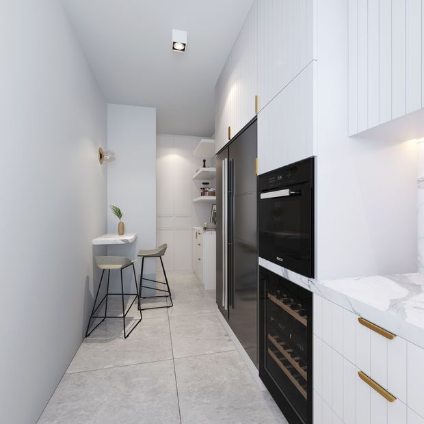 A narrow, modern galley kitchen with white vertical-groove cabinetry, integrated black appliances, and a white marble-look benchtop. Large pale grey floor tiles and grey walls create a clean, restrained palette. A compact breakfast nook with two stools sits along the left wall, while open shelving and pantry storage extend toward the rear.