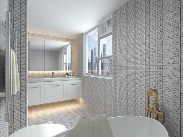 Bright contemporary bathroom with a freestanding white bathtub in the foreground, a gold-toned wall-mounted tap, white vanity cabinetry, large mirror, and geometric patterned tile covering the walls and floor. A window provides a city skyline view, while under-cabinet lighting adds warmth.