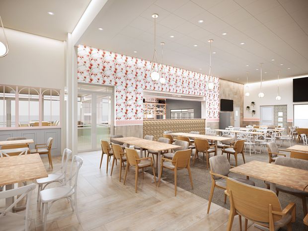 Bright contemporary restaurant or café interior with numerous timber tables and upholstered dining chairs, a patterned floral feature wall, a long tiled service counter with a textured front, pendant globe lights, pale timber-look flooring, and large glazed partitions. The space has a clean, airy, hospitality-focused fit-out with neutral tones and warm wood accents.