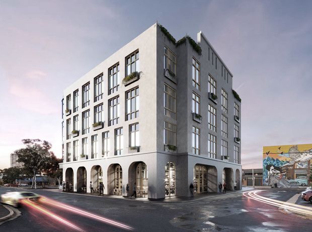 A rendered streetscape view of a contemporary multi-storey urban building with a pale masonry or rendered facade, large grid-pattern windows, planted window boxes and greenery along the roofline. The ground level has a series of tall rounded arches forming an active frontage with glazed entrances and shop or commercial interiors visible inside. The building occupies a street corner beside sidewalks, parked cars and a colourful mural on a neighbouring wall.
