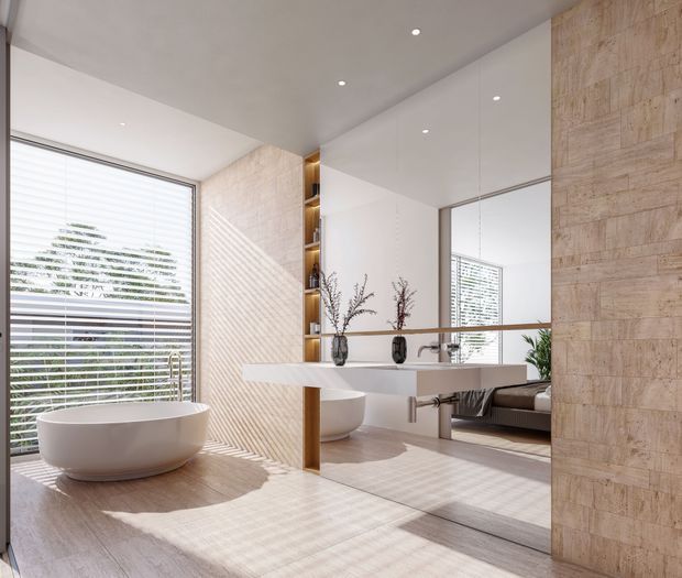 Bright contemporary bathroom featuring a freestanding white oval bathtub beside large horizontal blinds, a floating white vanity with integrated basin, wall-to-wall mirror, open timber shelving, and pale beige stone-look wall and floor finishes. The mirror reflects a bedroom area beyond, but the bathroom dominates the image.